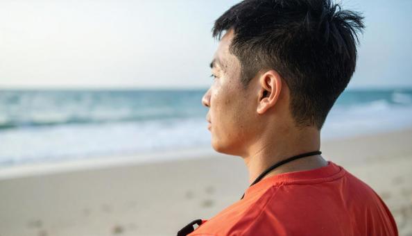 砂浜から海を見つめるライフセーバーの男性 砂浜から海を見つめるライフセーバーの男性の写真