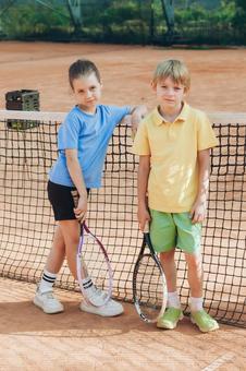 テニスネットを後ろに立つ子供たち 男の子,女の子,外国人の写真素材