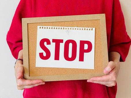 STOPと書かれたコルクボードを持つ女性 ストップ,止まれ,女性の写真素材