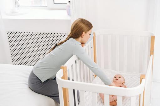 赤ちゃんを寝かせたままお世話をする女性 赤ちゃんを寝かせたままお世話をする女性 親子,女性,赤ちゃんの写真素材