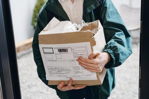 玄関で潰れた段ボール箱を抱える配達員の男性 配達,フードデリバリー,デリバリーの写真素材