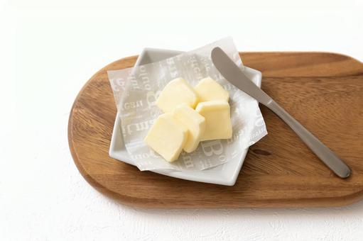 木のボードに乗せたバター+ナイフ バター,切れてるバター,バターナイフの写真素材