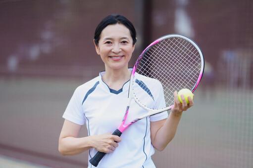 白いウェアでテニスを楽しむ女性 女性,テニス,ラケットの写真素材