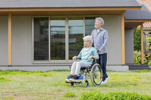 住宅の前を歩く車椅子に乗ったシニア夫婦 住宅の前を歩く車椅子に乗ったシニア夫婦 シニア,夫婦,車椅子の写真素材
