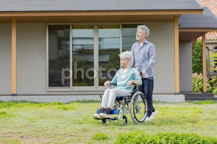 住宅の前を歩く車椅子に乗ったシニア夫婦 シニア,夫婦,車椅子の写真素材