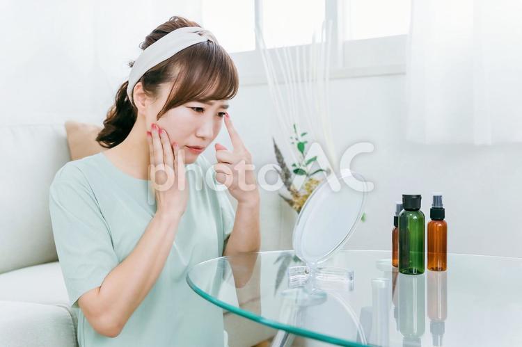 鏡を見て肌に悩む女性（目・目尻） 花粉症,充血,ドライアイの写真素材