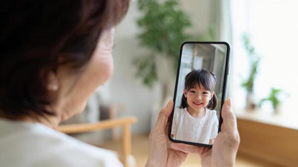 孫とテレビ電話をするおばあちゃん 孫とテレビ電話をするおばあちゃんの写真