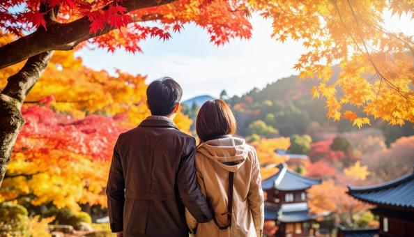 美しい紅葉を眺める夫婦の後ろ姿の写真