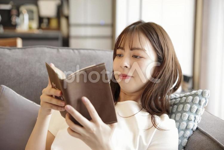 ソファに座って読書をする女性 読書,リラックス,集中の写真素材