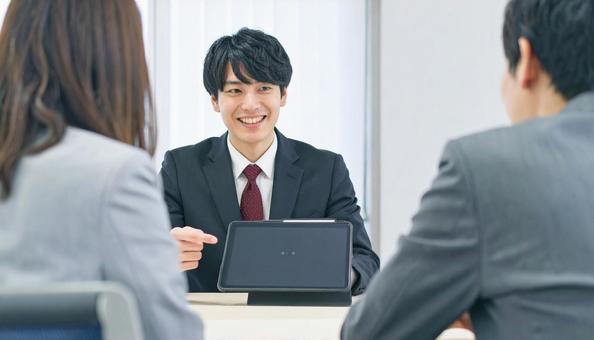 タブレットを使って説明する男性営業マン タブレットを使って説明する男性営業マンの写真