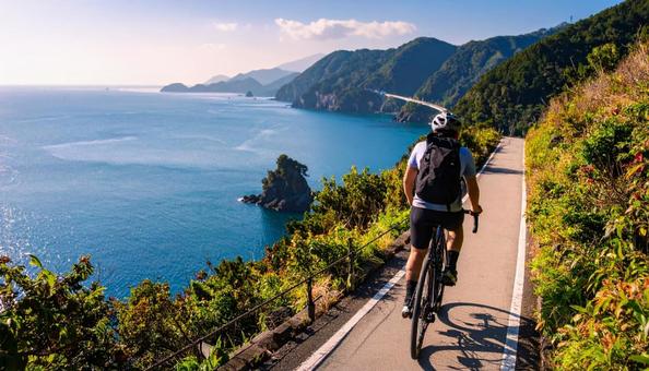 休日に海辺をサイクリングする男性 休日に海辺をサイクリングする男性の写真