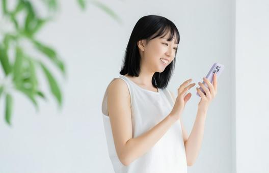 リビングでスマホを使う女性 リビングでスマホを使う女性の写真