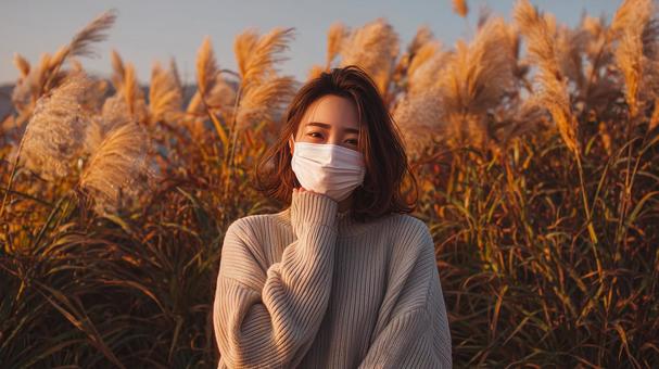 秋風に揺れるススキとマスク姿の女性 秋風に揺れるススキとマスク姿の女性の写真