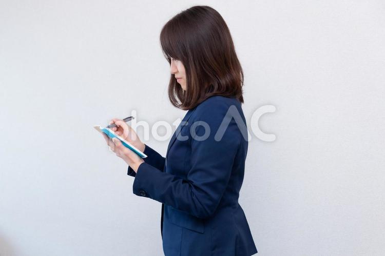 メモをとるスーツの女性　横 女性,スーツ,メモ帳の写真素材