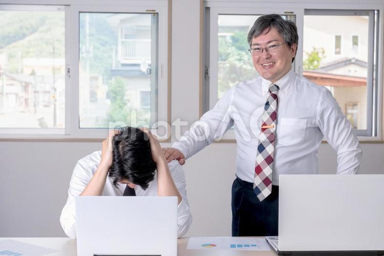 頭を抱える男性と笑顔で方に手を置く男性 パワハラ,ビジネスマン,会社員の写真素材
