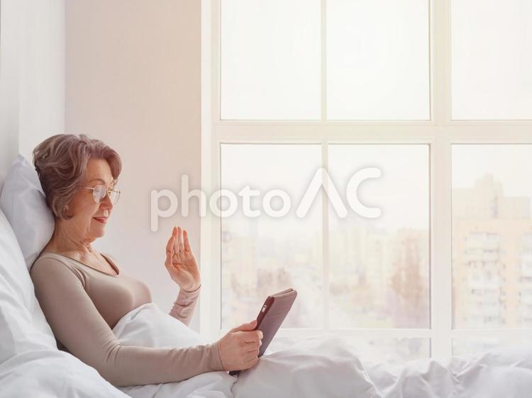 タブレットに手を振るシニア女性（太陽） 女性,タブレット,見るの写真素材
