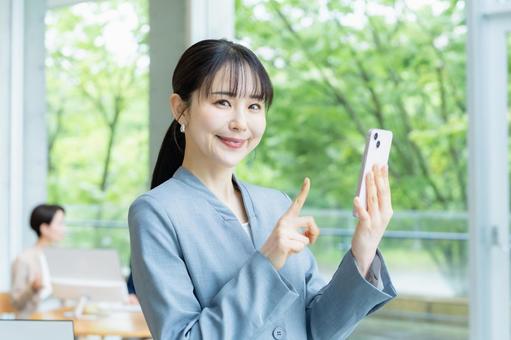 スマホを操作するビジネスウーマン スマホ,笑顔,ビジネスウーマンの写真素材
