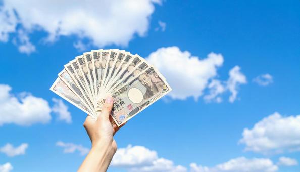 一万円を持つ手 青空背景 一万円を持つ手 青空背景の写真