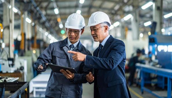 町工場で働く作業服のシニア社長と若い社員 町工場で働く作業服のシニア社長と若い社員の写真