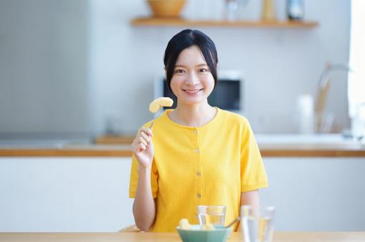 皮を剥いたリンゴを持つ笑顔の女性の写真