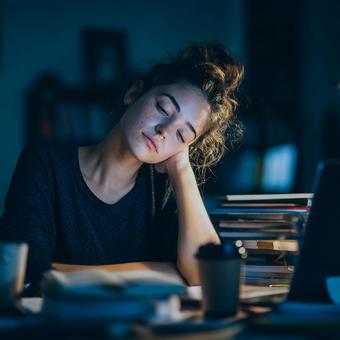 深夜まで勉強（仕事）をして疲れ果てた女性の写真