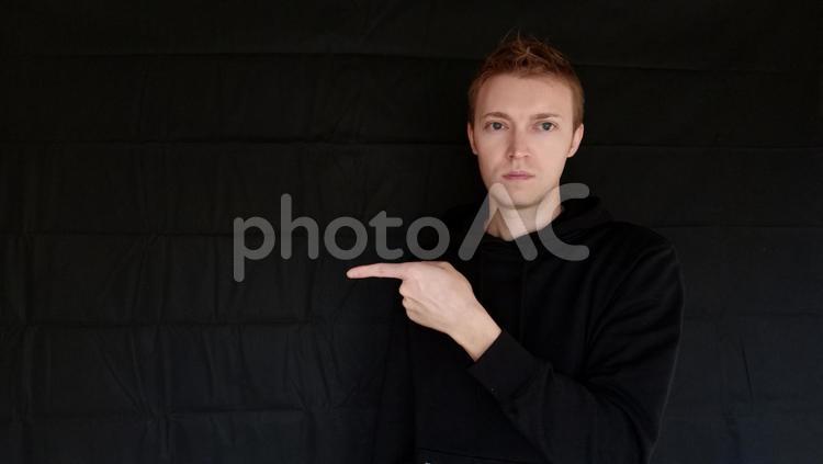 左・あっち　指さしで方向を教えてる外国人男性　黒バック 左,ひだり,あっちの写真素材