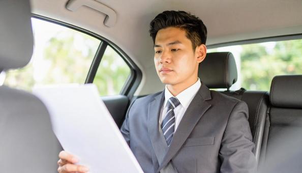 手もとに書類を持って運転するサラリーマン 手もとに書類を持って運転するサラリーマンの写真