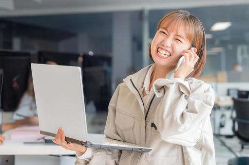 笑顔で電話する作業服女性 笑顔で電話する作業服女性 受付,電話,パソコンの写真素材
