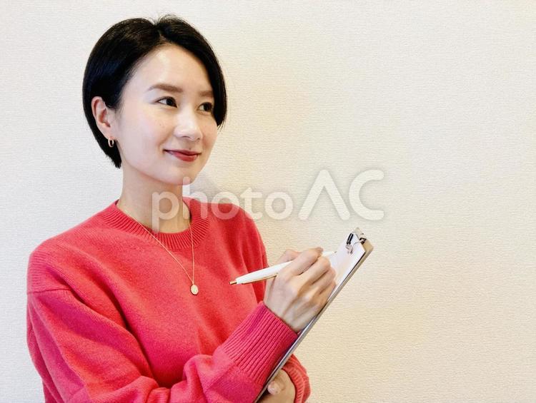 バインダーを持ちながらメモをとる女性 女性,笑顔,微笑みの写真素材