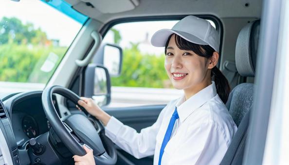 ハンドルを握る可愛い配送スタッフの女性の写真