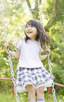 ブランコで遊ぶ笑顔の女の子 ブランコで遊ぶ笑顔の女の子の写真