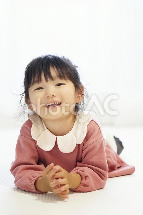 寝転んだ笑顔の女の子 子供,女の子,3歳の写真素材