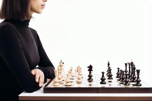 チェスをしている黒いタートルネックの横向きの女性（白背景） チェス,女性,20代の写真素材