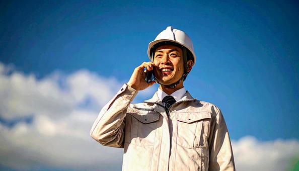 電話をする作業員 電話をする作業員の写真