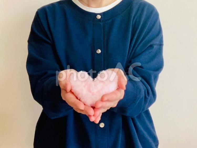 ハートを両手に持つ女性（紺トップス） ハート,女性,思いやりの写真素材