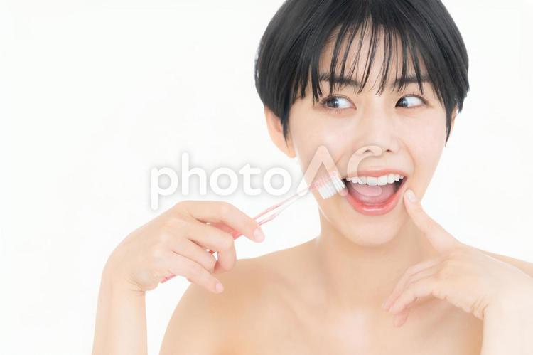 歯磨きをする白バックの若い女性 ホワイトニング,女性,オーラルケアの写真素材