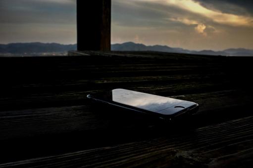 <素材>夕暮れのベンチの忘れられたスマホ <素材>夕暮れのベンチの忘れられたスマホの写真