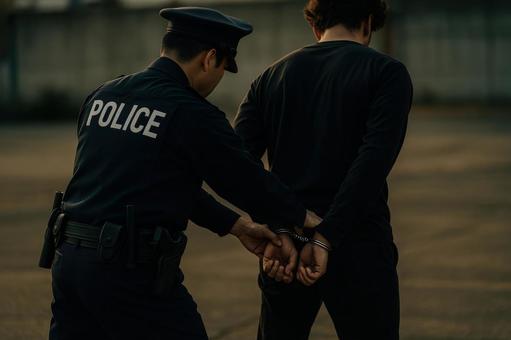 犯人役に手錠をかける警察官 犯人役に手錠をかける警察官の写真