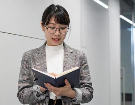 歩きながらノートに書くビジネスウーマン 歩きながらノートに書くビジネスウーマンの写真