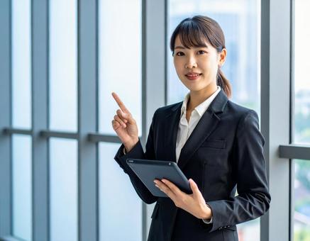 タブレットを片手に提案する女性 タブレットを片手に提案する女性の写真
