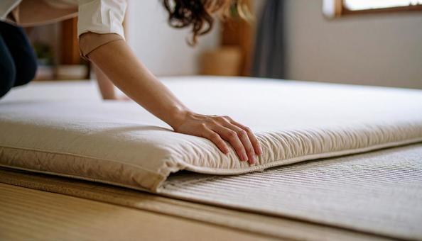 布団にカバーをかぶせている日本人女性の写真