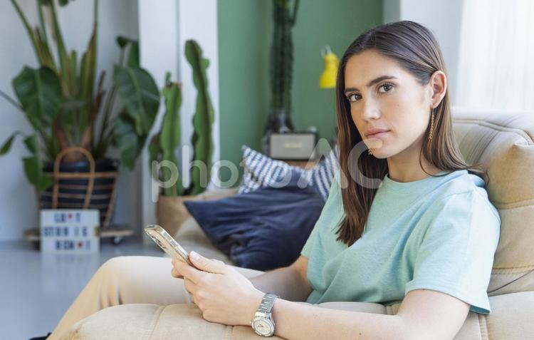 スマホを持ちカメラ目線の女性 女性,寛ぐ,スマホの写真素材