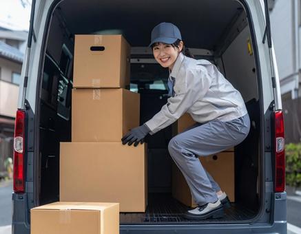 トラックから荷物を出す宅配女性ドライバー トラックから荷物を出す宅配女性ドライバーの写真