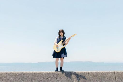海辺でエレキギターを演奏する女子高校生 女子高校生,高校生,エレキギターの写真素材