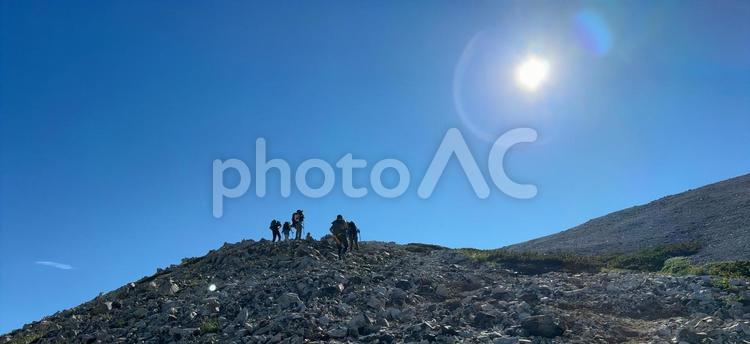 青空と太陽を背に立つ登山者たち 登山,山頂,シルエットの写真素材