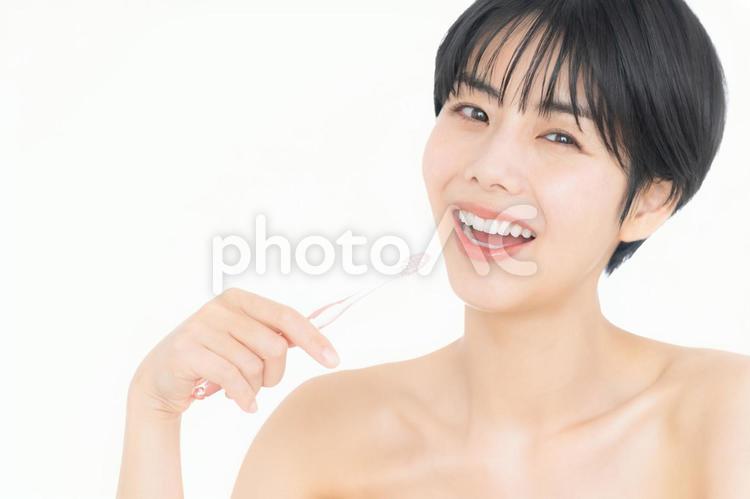 歯磨きをする白バックの若い女性 ホワイトニング,女性,オーラルケアの写真素材