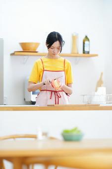 キッチンでフルーツの皮むきをしている女性 女性,真剣,リンゴの写真素材