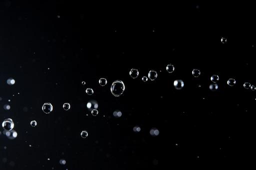 浮かび上がる黒背景の水滴の写真