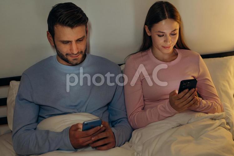 携帯を持って見ているカップル 男性,女性,もたれるの写真素材