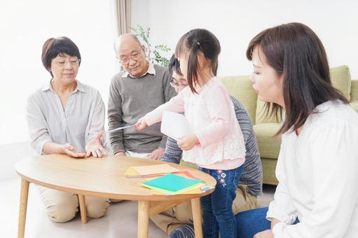 折り紙で遊ぶ子供と家族 折り紙で遊ぶ子供と家族 一人娘,祖父母,紙の写真素材